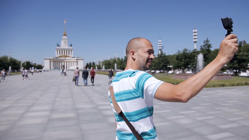 A young guy, a tourist, walks around the square and takes everything on