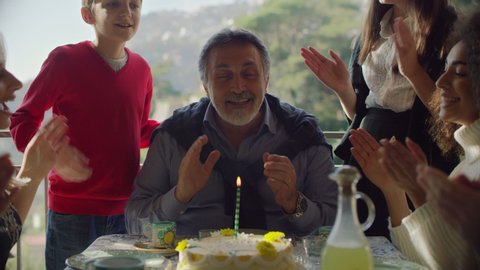 Italian family celebrating a birthday with cake and limoncello, with view of Amalfi coast in background. Medium shot on 8k helium RED camera.