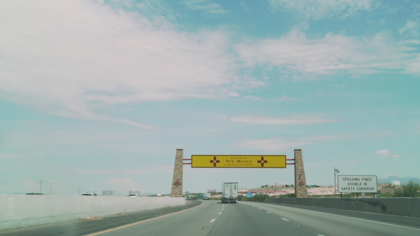 New Mexico state border sign on highway, driving POV
