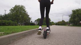 Fit Woman rides electric scooter - Full back follow shot of Modern transportation gadget and popular futuristic device among young people