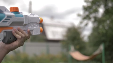 funny boy shoots a water pistol outdoors close up