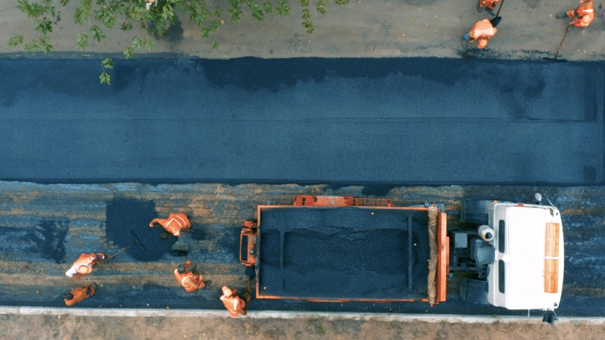 Aerial top view of roadworks with road workers lay asphalt. Road works
