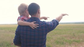 happy family. slow motion video training father and son teamwork concept. father holds his son in his arms shows into lifestyle the distance his hand on the horizon nature outdoors. happy family man
