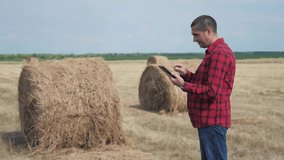 smart farming agriculture concept. man farmer worker studying a haystack in a field on digital tablet. slow motion video. male lifestyle agronomist botanist farmer working in the field