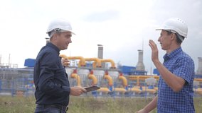 teamwork. industry gas production station concept. slow motion video victory success. two engineers in helmets shaking hands on a gas supply business contract. two workers work at the factory
