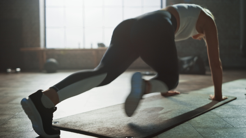 Beautiful and Young Girl Does Running Plank on Her Fitness Mat. Athletic Woman Does Mountain Climber Workout in Stylish Hardcore Gym Royalty-Free Stock Footage #1035271577