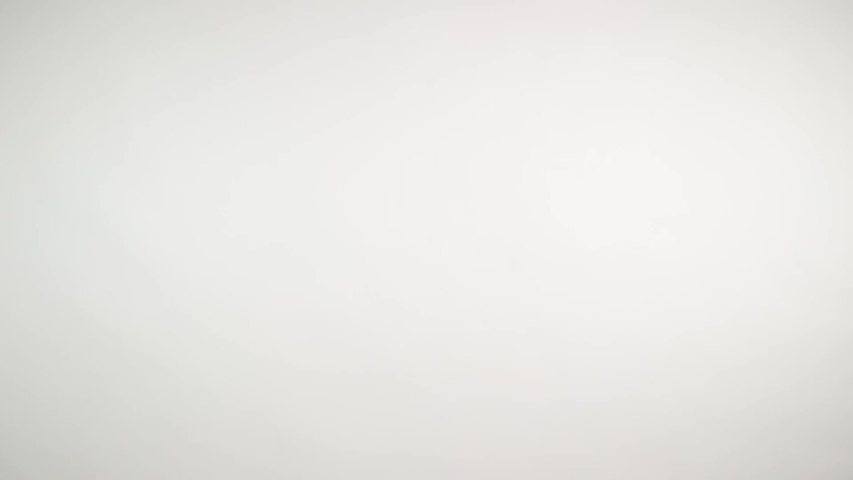Birthday kid holds a gift and blows noisemaker. Lovely young girl wearing birthday cap over white background