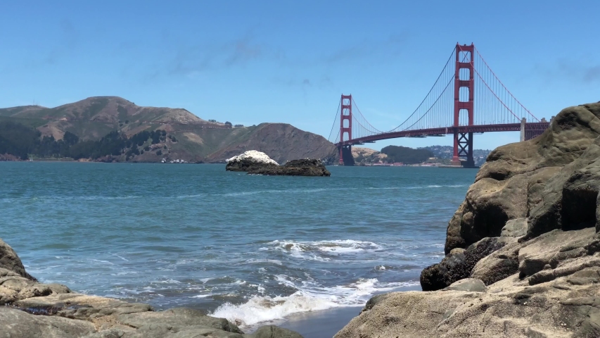 Waves crashing the rocks at Baker beach with Golden Gate bridge at background