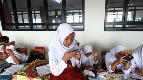 bekasi , jawa barat / Indonesia - 05 24 2019: Students play handphones when teacheris not in class. Back to school concept