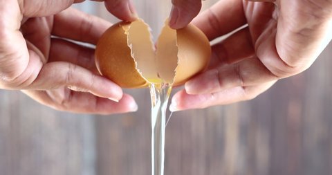 Hands are cracking an egg for cooking.