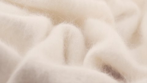 Soft Wool background. Alpaca wool mohair clothes texture closeup. Natural Cashmere Soft and fluffy merino wool macro shot. Woolen fabric. Knitted hairy detail texture surface Rotated. 4K UHD slowmo