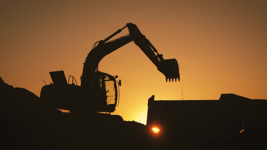 Silhouette of an excavator that loads sand into a truck at sunset. Concept construction and heavy industry, machine will be used in heavy industry business. Slow motion footage. Royalty-Free Stock Footage #1035308975