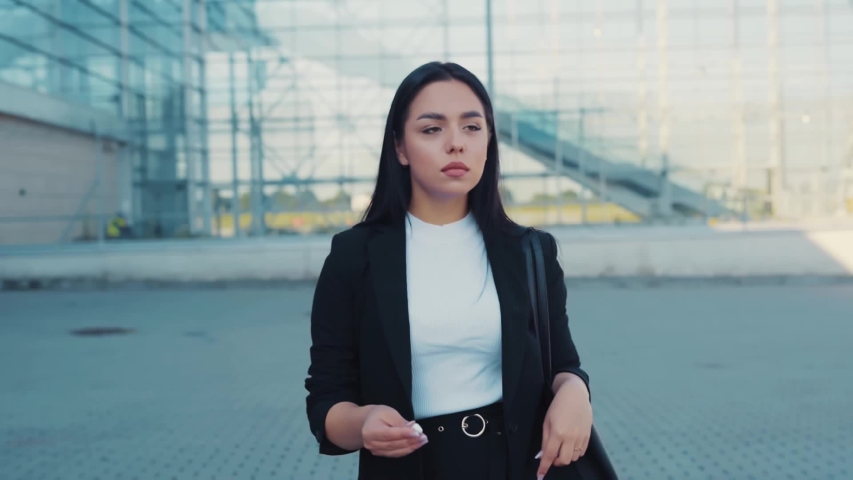 Close up slow motion view of good looking young seductive woman putting on headphones, listening to music while walking home, distracting herself from the street city noise. Gadgets concept