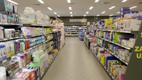 Szczecin / Poland - 05 25 2019: First person view walking aisle in empty Netto superstore. Rows of household goods & products lined up on organised shelves with store advertising.