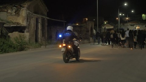 Mytilene / Greece - 04 26 2019: Police biker driving behind group of people walking