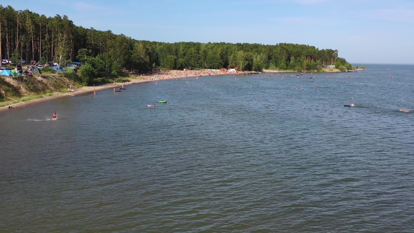 Top view of the beach, featuring colorful umbrellas and people relaxing on a summer day. Hot day, many people sunbathe and swim