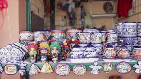 Slow panoramic view from right to left. Mexican Accessories market with ceramic plates and head skulls decorated in traditional Mexico style. Cholula, Puebla Mexico