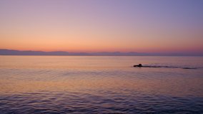 Beautiful view of the sunrise by the Ionian sea in Corfu, Greece. A man swimming in the sea. ProRes 10 bit. 4K UHD video.