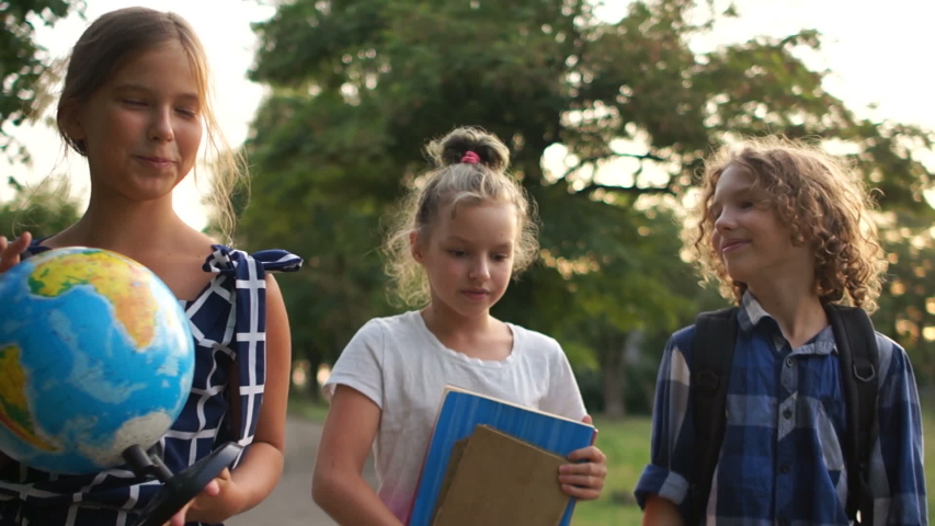 Three school friends go to school, happy children have fun talking to each other, back to school