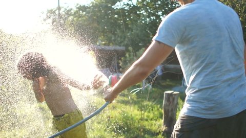Fathers day. A man enjoys a summer vacation with his son, father and son water each other from a hose