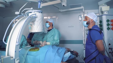 Group of doctors perform an operation to a patient. Surgeons in medical uniform and masks working in the operating room. Neurosurgery.