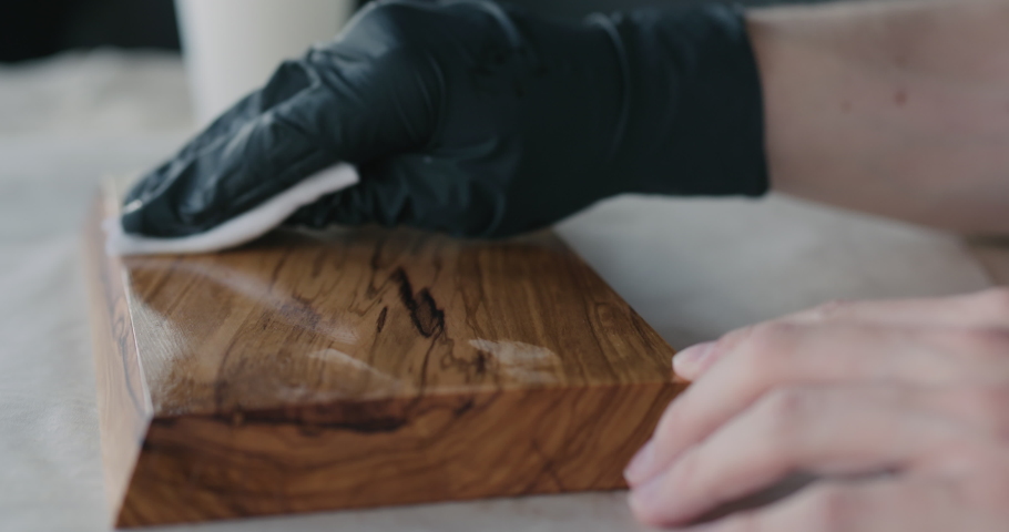 Slow motion woodworker applying oil finish to olive wood board
