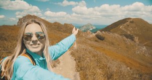 Woman tourist traveler walking on the top of mountain in summer sunny day under sun light. Beautiful mountains landscape view. 4K slow motion video, Concept follow me freedom.