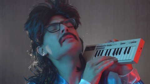 Man with mustache and mullet from the 70s 80s 90 playing on his retro synth keyboard. Vintage concept.
