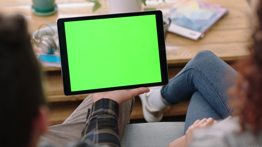 Close up couple hands using digital tablet computer watching green screen entertainment on mobile device enjoying relaxing at home viewing chroma key