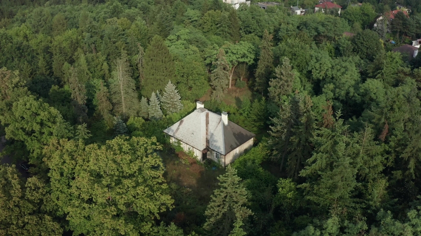 Aerial view of an old abandoned house in the forest. Cinematic shot of a lonely house surrounded by trees. Drone Shot 4K.