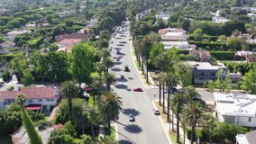 Beverly Hills transportation - Aerial 4k b-roll clip over cars driving up the beautiful, palm tree lined Beverly Drive. Tourism, holidays, real estate advertising, travel, vans, drones, business ads.