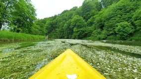 Yellow canoe in beautiful green river with dense forests around