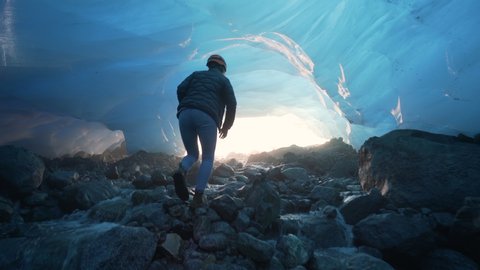 Pan Left to Right: Woman Walking UP the Cold Watery Area of Mendenhall Glacier in Alaska With Ice Formed Above