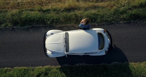 PEDASO, ITALY - AUGUST 2019: Old Volkswagen Beetle top down aerial view with couple in the countryside.