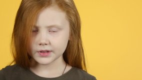 Close-up of kid screams and looking at the camera on a yellow background. Slow motion