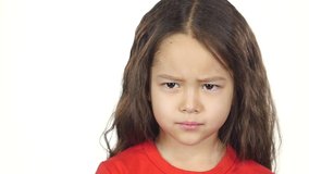Close-up of little girl in red T-shirt shows emotion, crosses hands posing at white background. Little girl crosses hands with offended or indignant . Slow motion