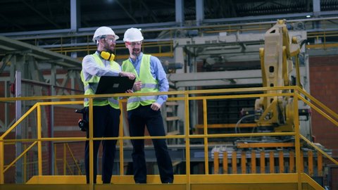 Two workers are talking in the modern factory facility