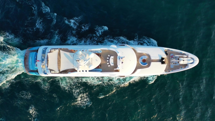 Aerial drone tracking top down video of luxury yacht cruising in deep blue open ocean sea