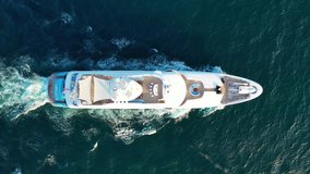 Aerial drone  tracking top down video of luxury yacht cruising in deep blue open ocean sea
