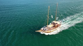 Aerial drone view video of small vintage wooden schooner sailing boat in Balearic islands