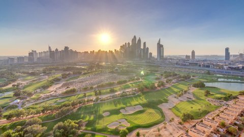 Dubai Marina skyscrapers and golf course sunset timelapse, Dubai, United Arab Emirates. Aerial view from Greens district. Rays of light and orange sky