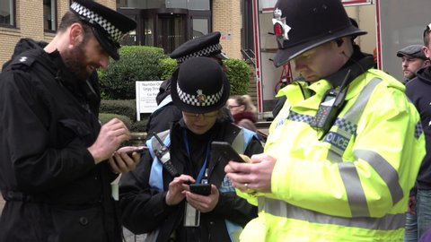Chelmsford / United Kingdom (UK) - 02 06 2019: Police officers stand in a group using mobile phones
