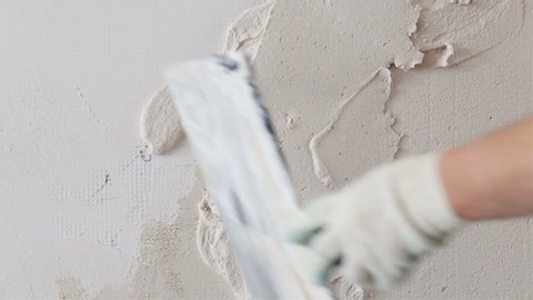 Construction worker with long trowel plastering a wall