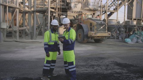 Two construction engineers checking crushed stone shipment using digital tablet at construction site