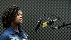 African american alfro hair black Woman sing a song loudly and express feeling with power sound over hanging microphone condenser. Egg Crate Studio low lighting shadow Sound Proof Absorbing wall room