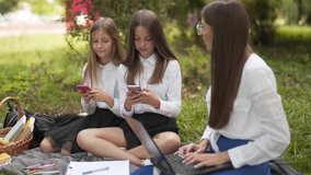 Woman teaching young school girls distracted by phones in outdoor scene