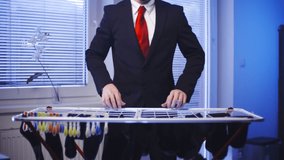 Businessman doing laundry housework. Medium shot of headless male businessman in focus while hanging socks after washing. Windows in background