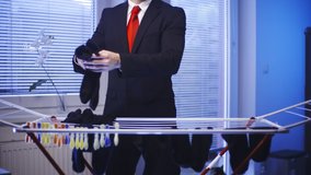 Businessman hand washed clothes doing housework. Medium shot of headless male businessman in focus while picking hanged black socks. Windows in background