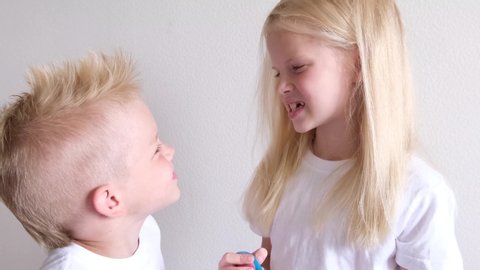 Little cute blonde girl and boy are brushing teeth. Fun lifestile play dentist game. Children smile. Health care, dental hygiene