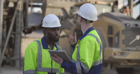 Two industrial engineers reviewing documents on a tablet during an inspection at construction site